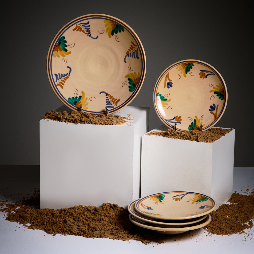 Decorative ceramic plates with artistic designs on a white pedestal against a dark background