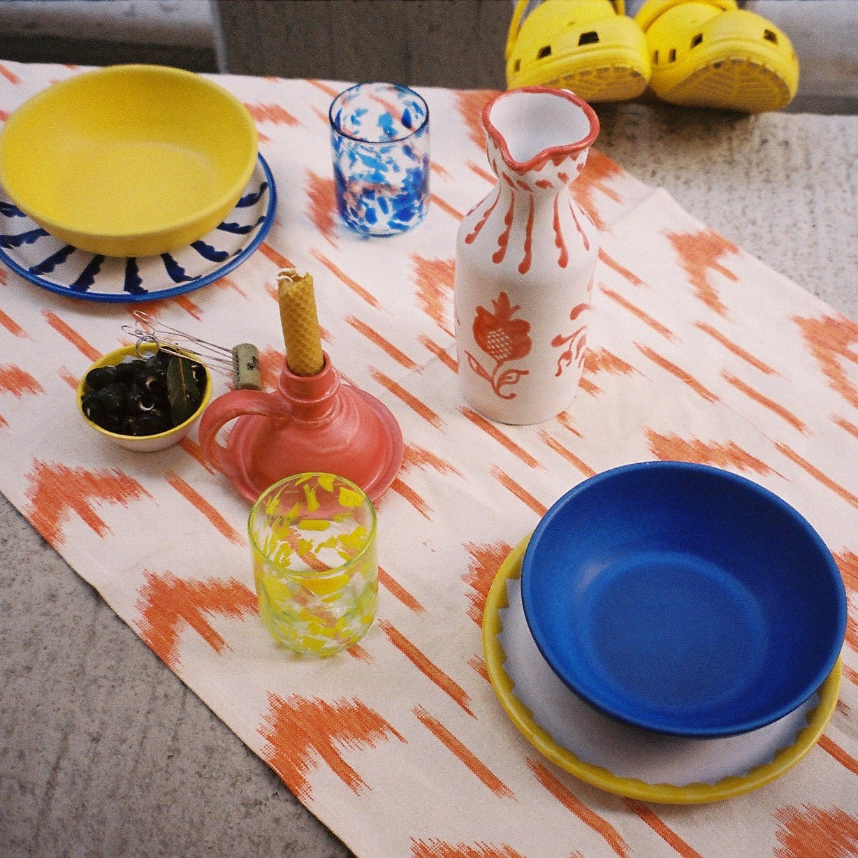 Colorful table setting with plates, cups, and a teapot on a patterned tablecloth. - lifestyle - lifestyle
