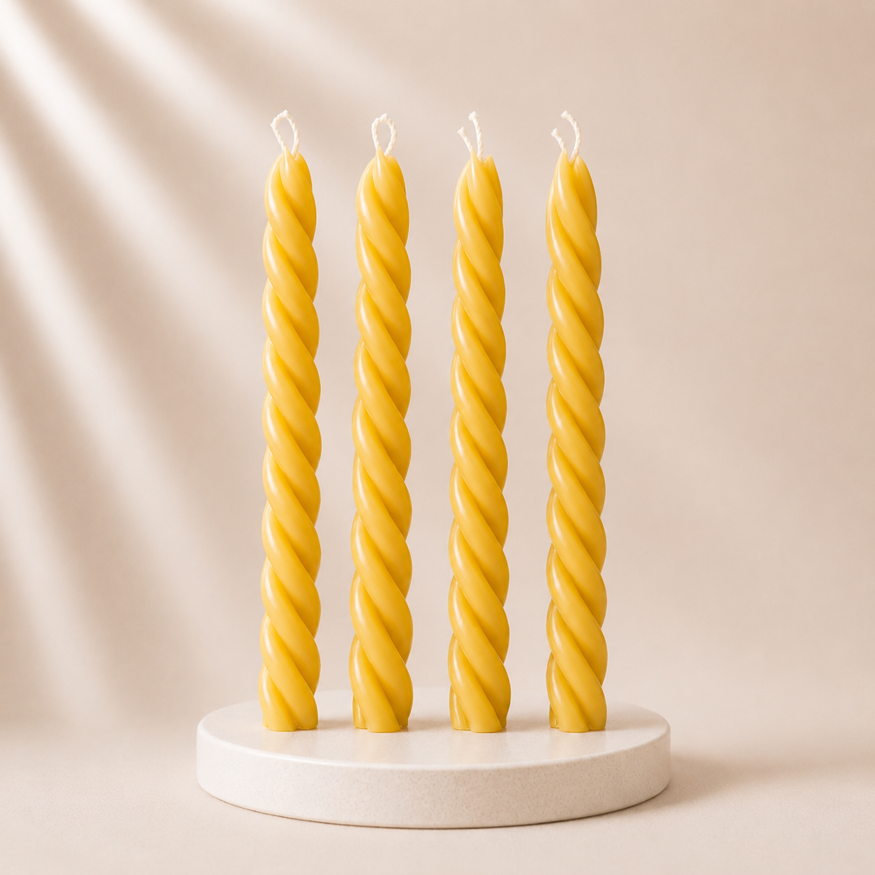 Four twisted yellow candles on a white stand against a beige background