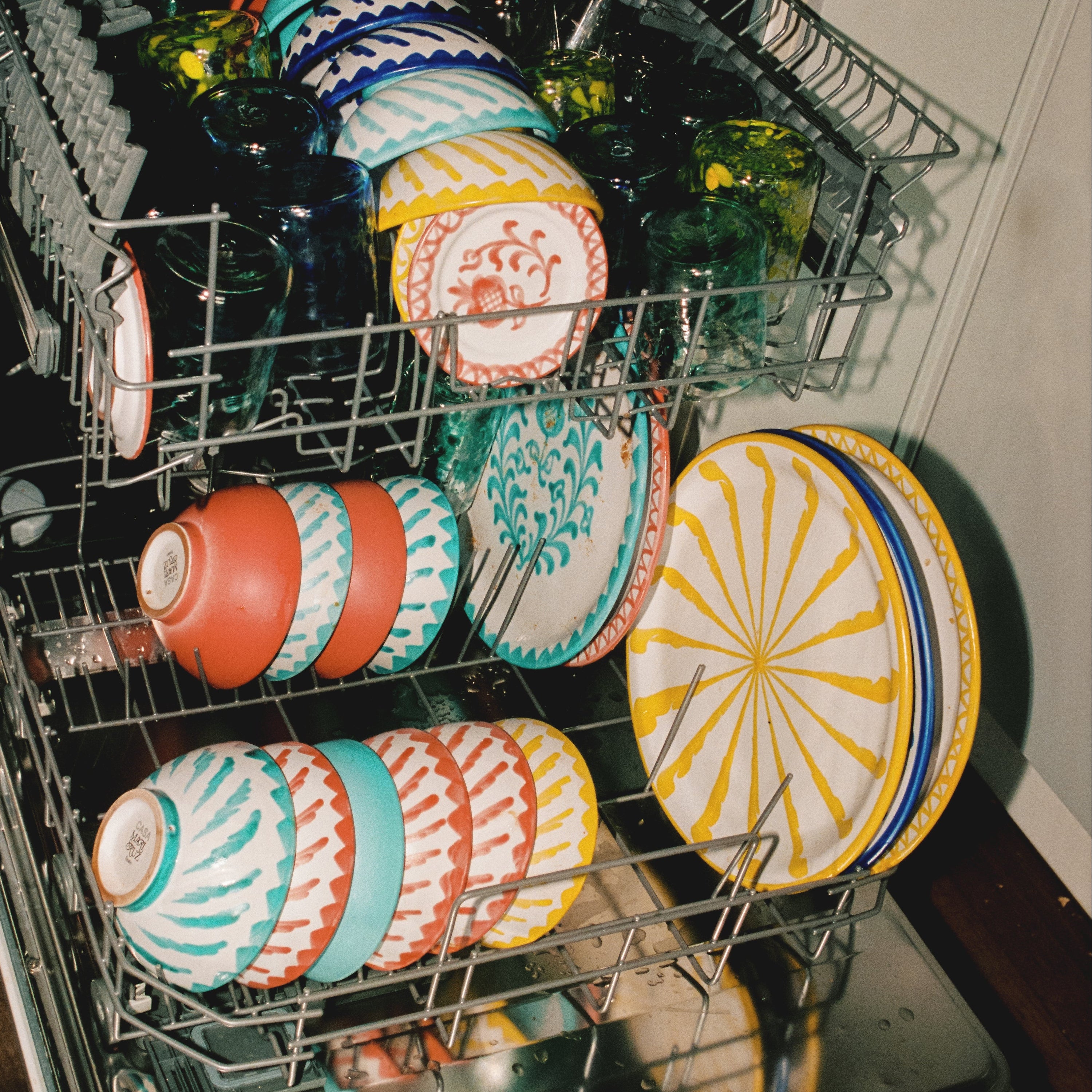Open dishwasher with colorful plates inside - lifestyle