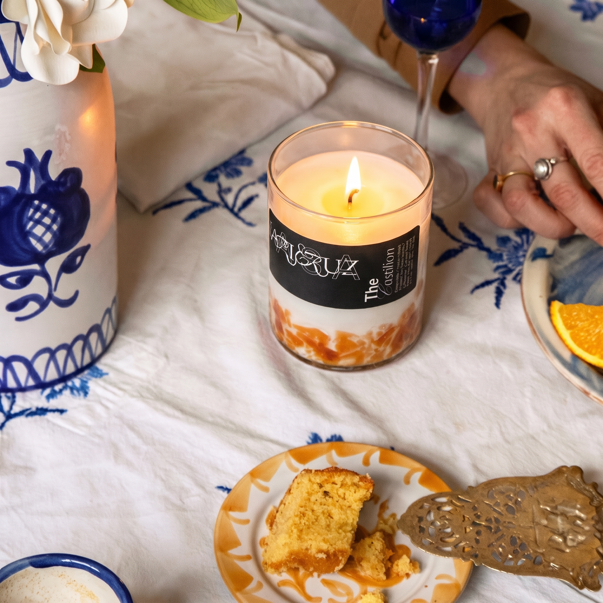 candle in orange halfway glass set in a blue table. - lifestyle