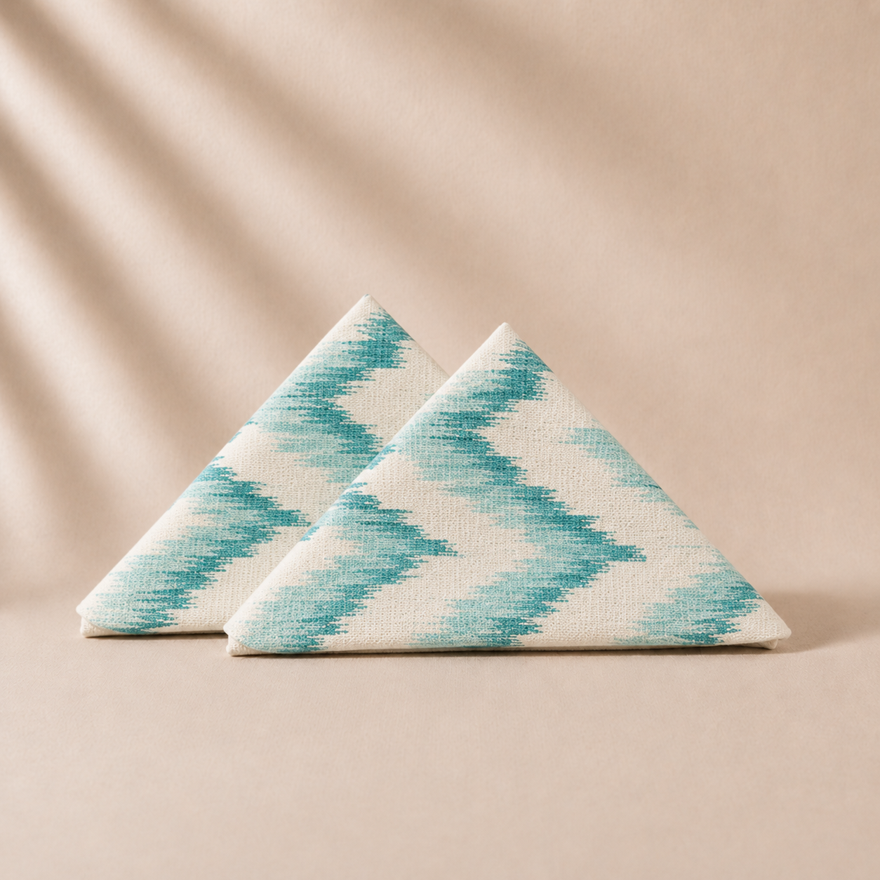 Two triangular napkins with a blue and white pattern on a beige background
