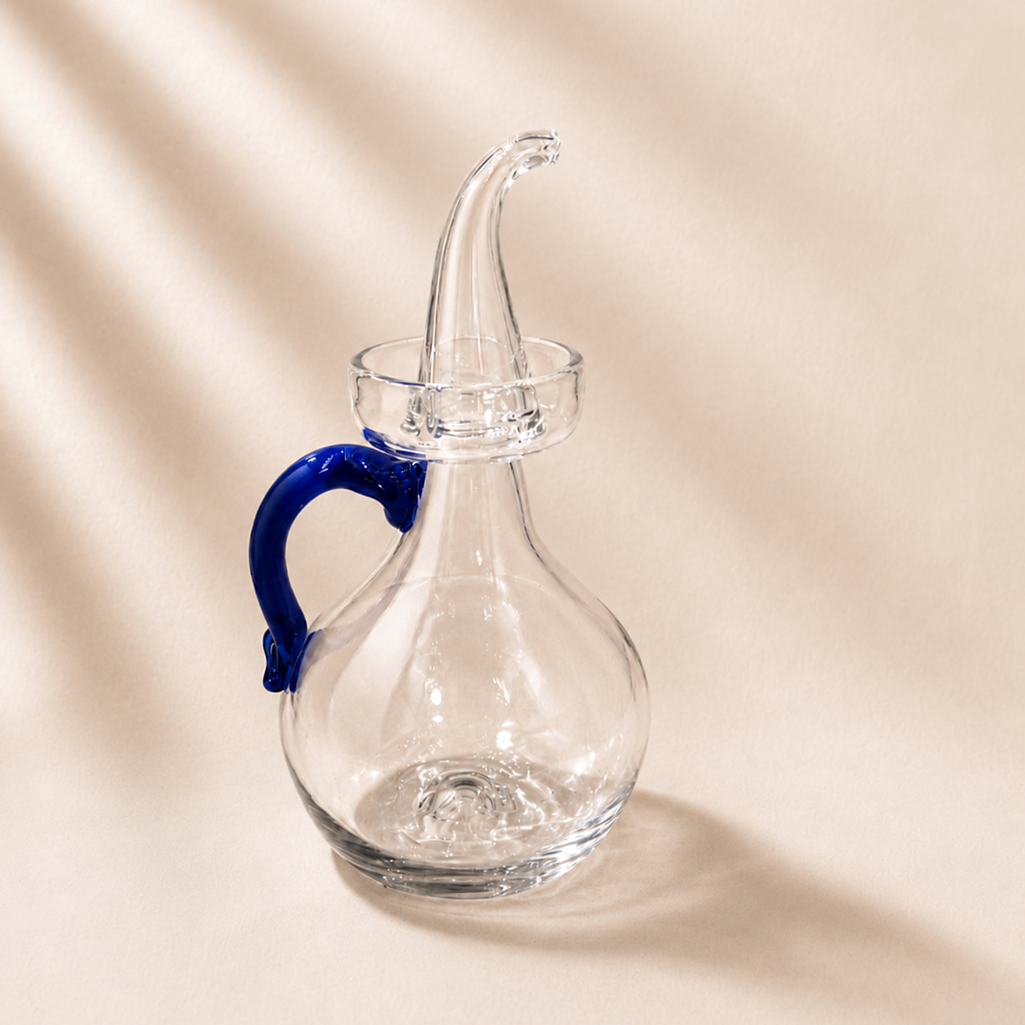 Olive cruet with a blue handle on a beige background