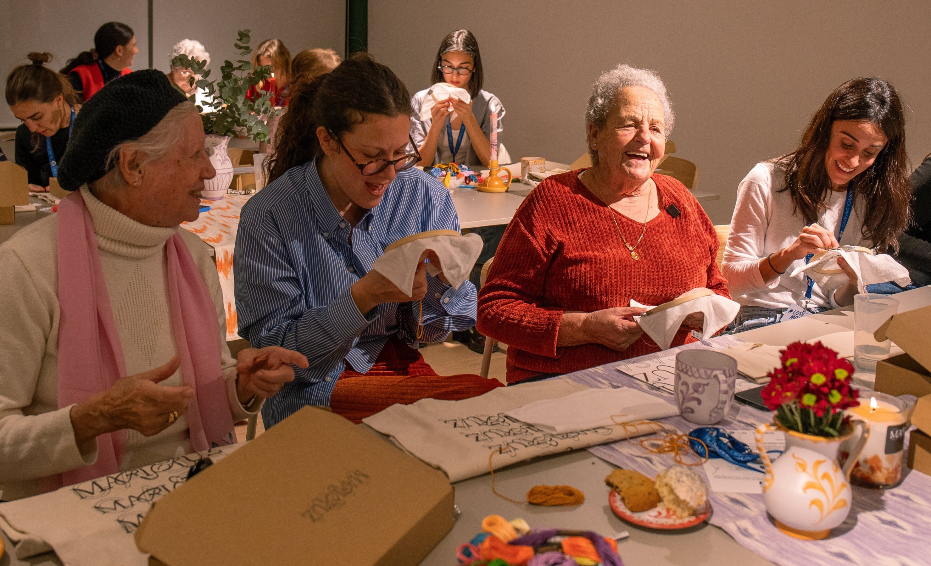 Group of people sitting at a table, engaged in an activity with various items on the table.