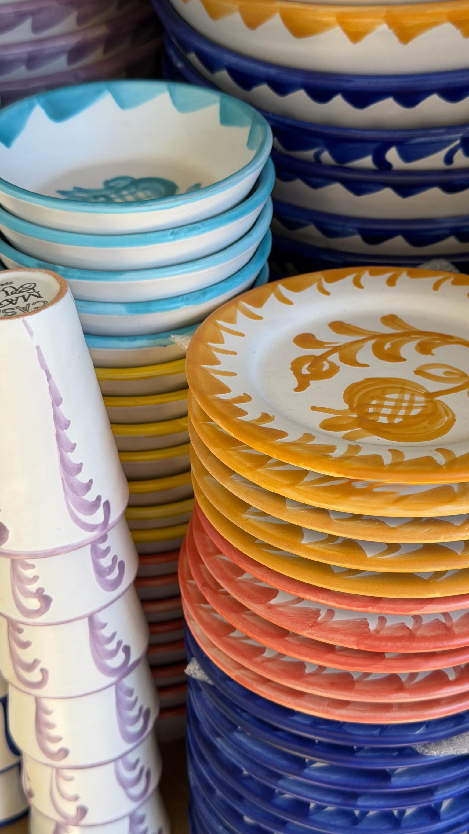 Stacks of colorful ceramic plates and bowls with decorative patterns.