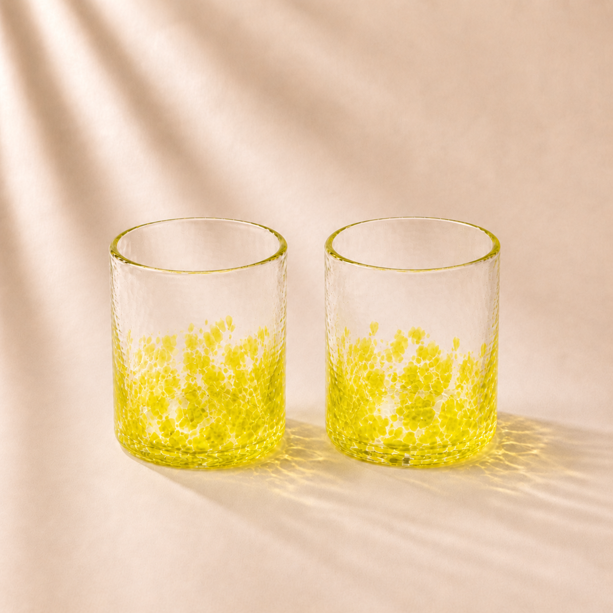 Two clear glasses with yellow interior on a beige background