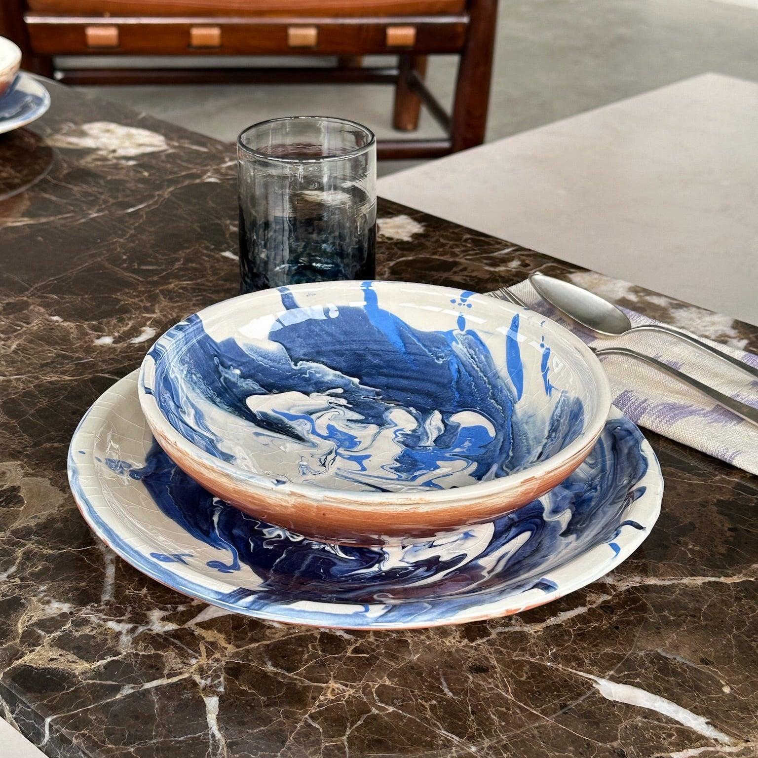 Blue and white ceramic bowl on a marble surface with a brown leather chair in the background.