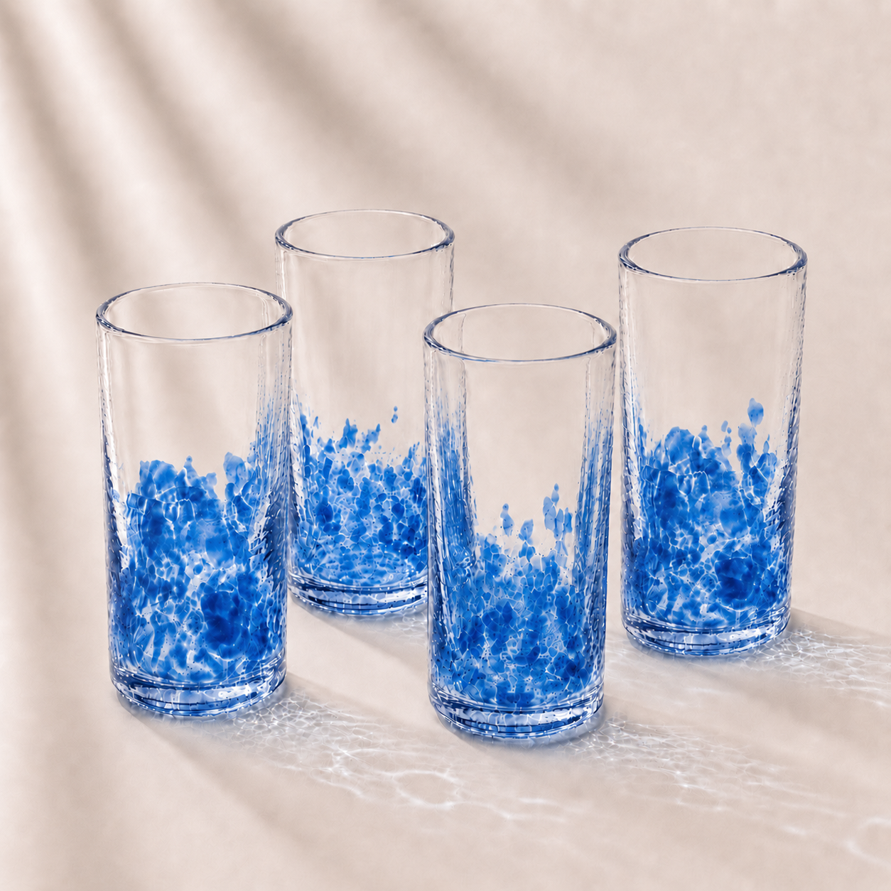 Four clear glasses with blue abstract designs on a beige background