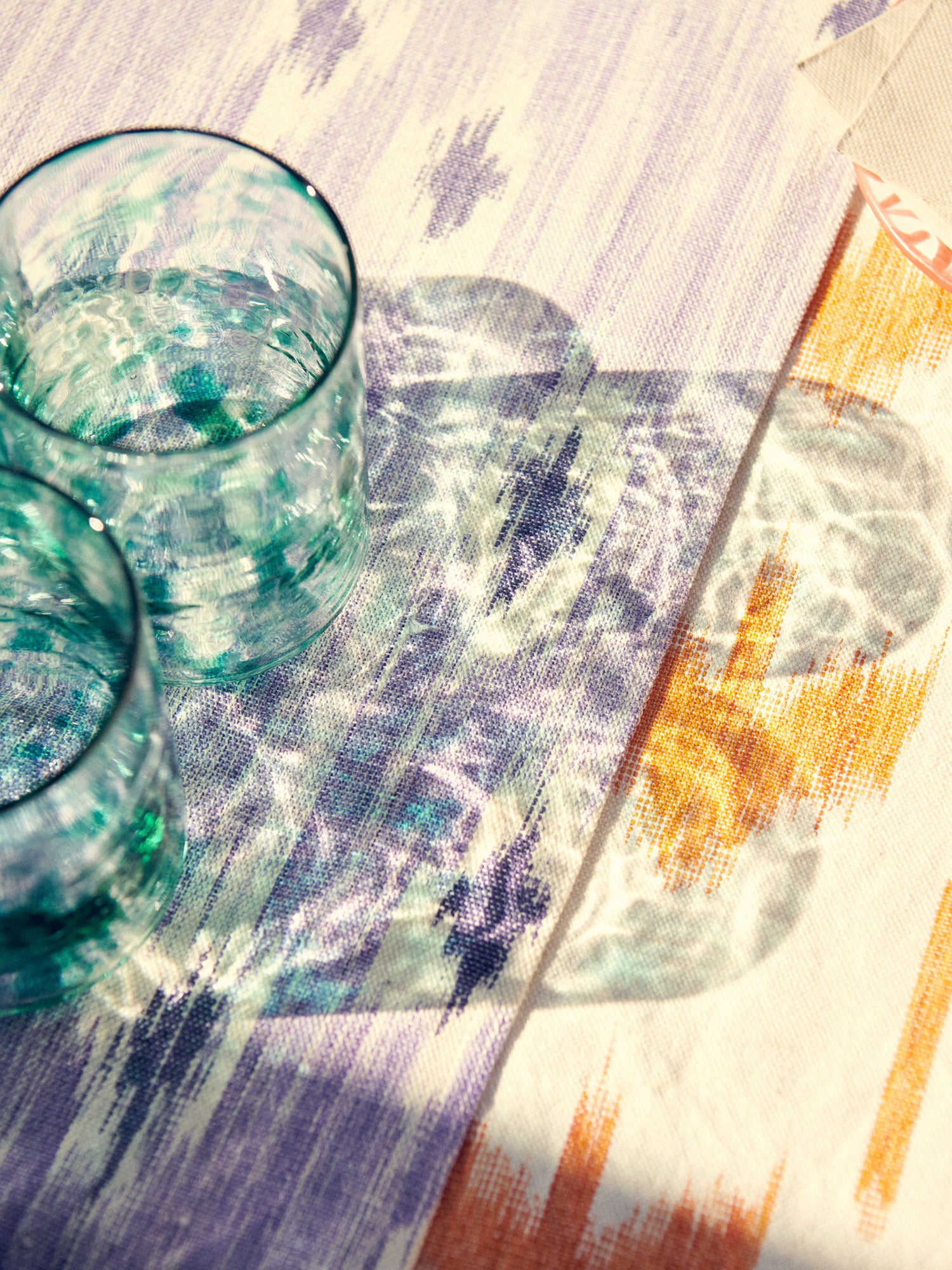 Two glass tumblers on a colorful patterned tablecloth