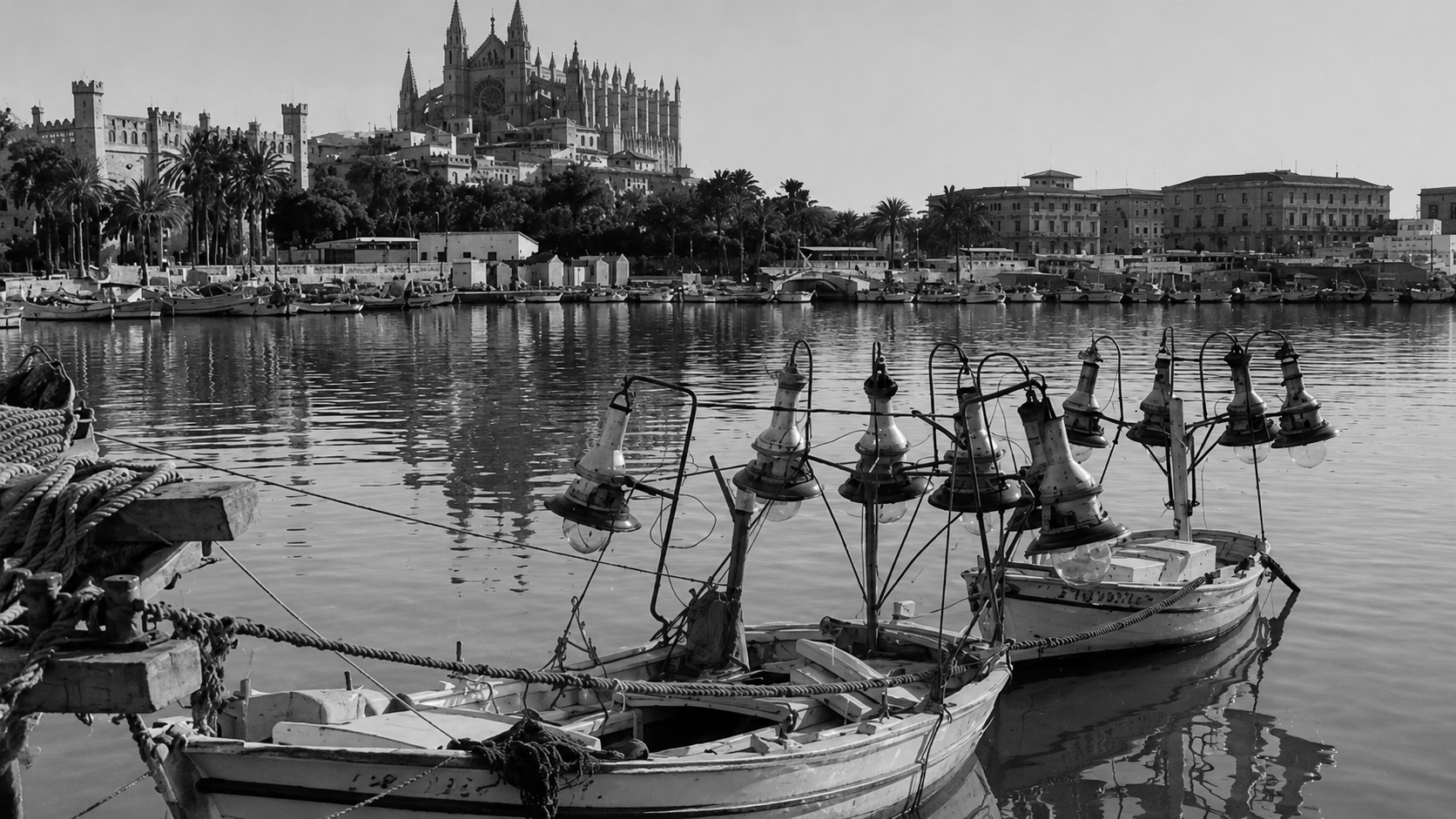 Black and white image of a harbor with boats and a cityscape in the background