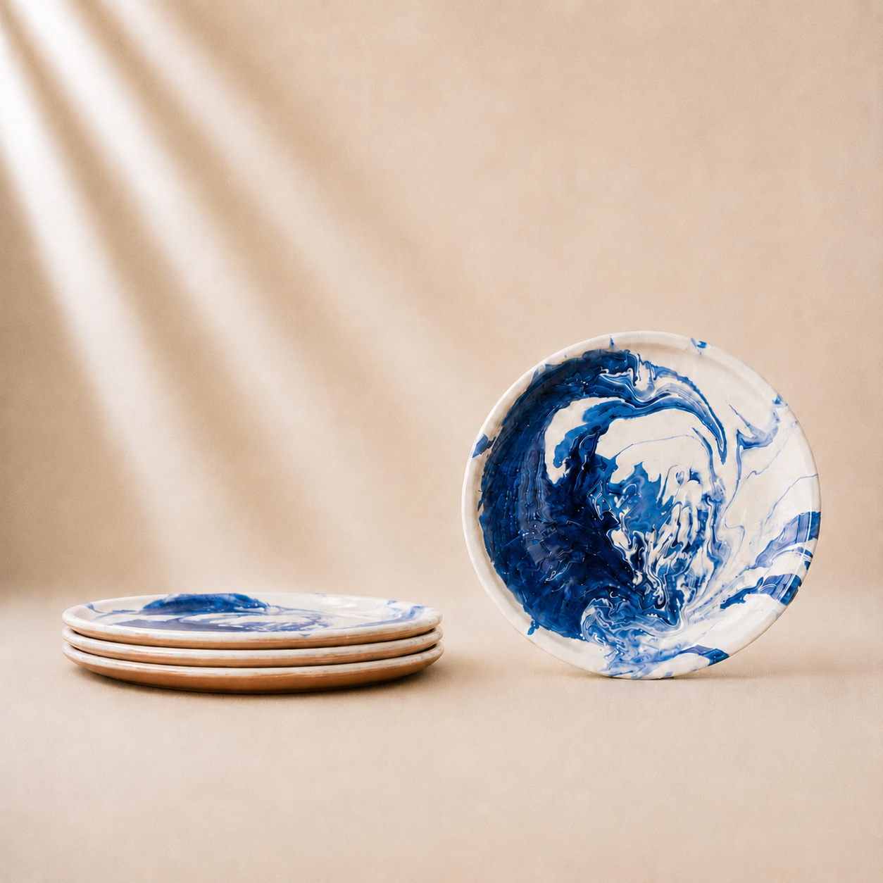 Set of ceramic plates with blue and white marbled design on a beige background