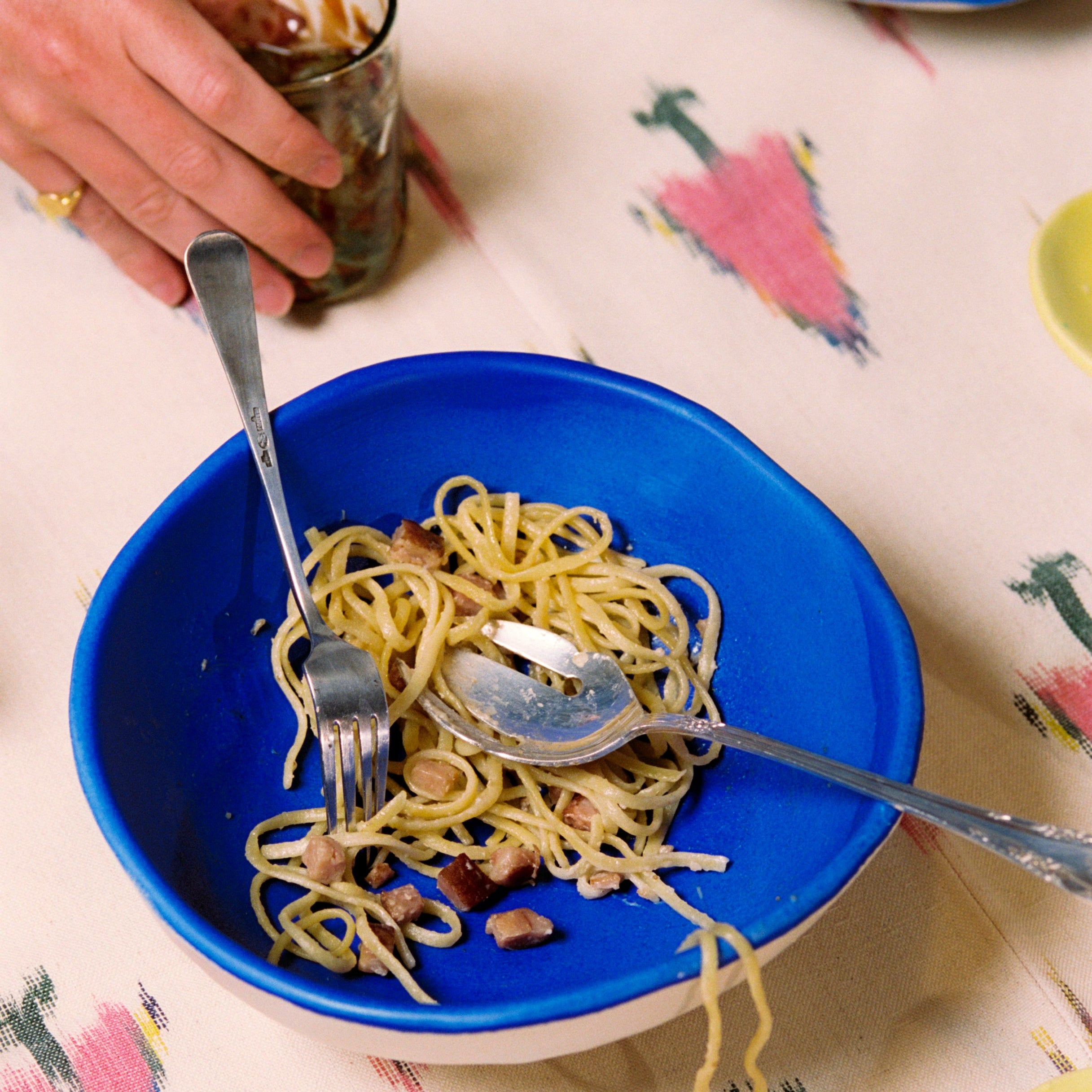 Blue plate with spaghetti and cutlery on a patterned tablecloth - lifestyle