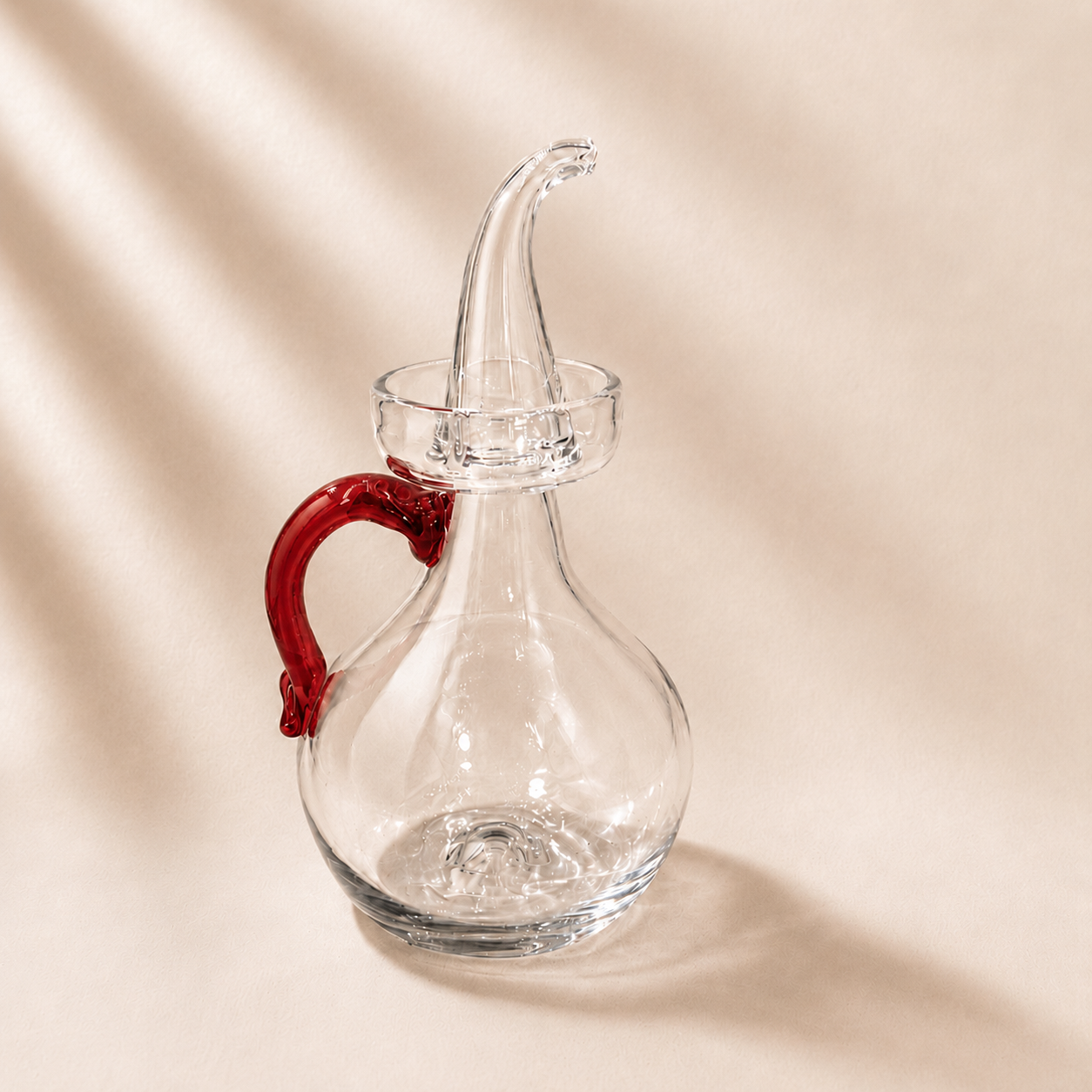 Clear olive cruet with red handle on a beige background