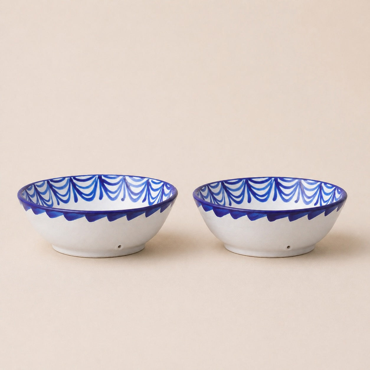Two white bowls with blue decorative rims on a beige background