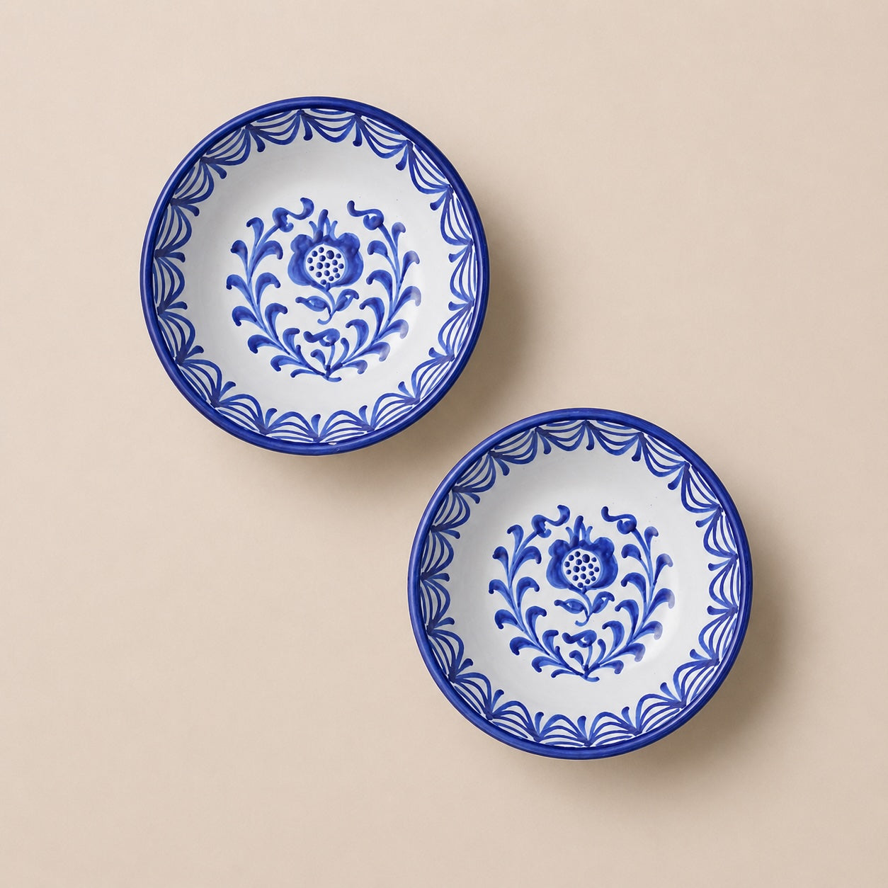 Two blue and white ceramic plates with floral patterns on a beige background