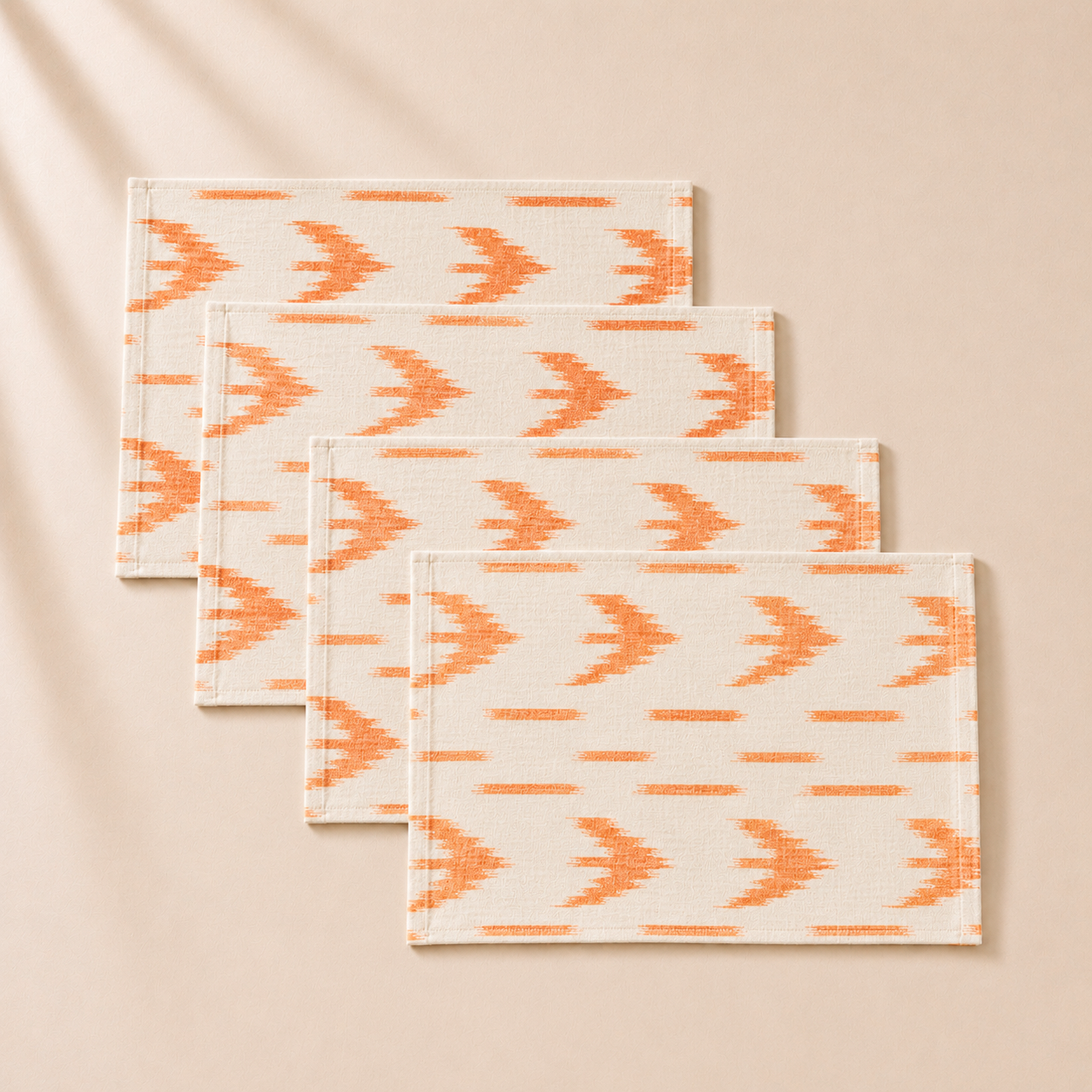 Set of four orange and beige patterned placemats on a beige background
