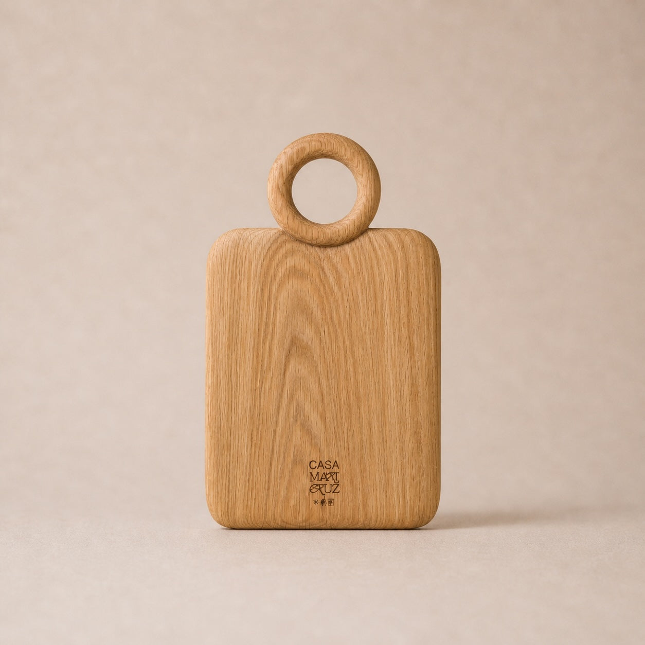 Wooden cutting board with ring handle on a beige background