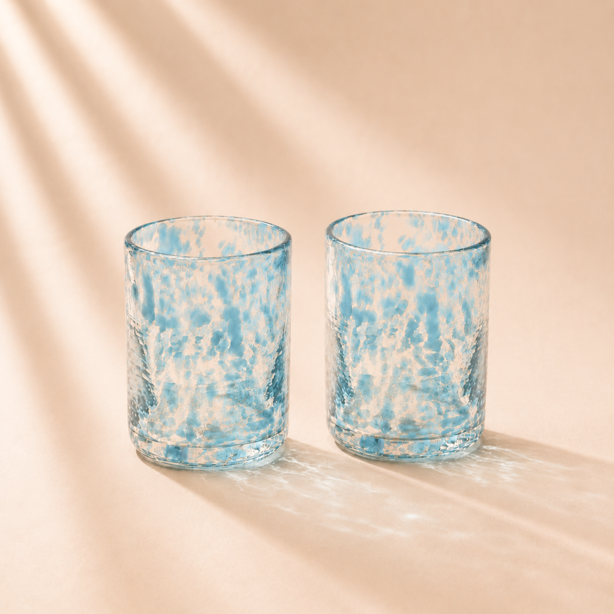 Two blue and white marbled glass tumblers on a beige background