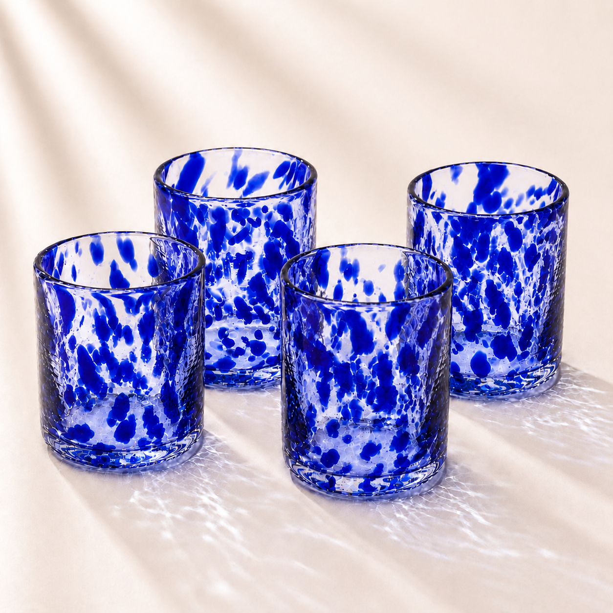 Four blue and white spotted glass tumblers on a light background
