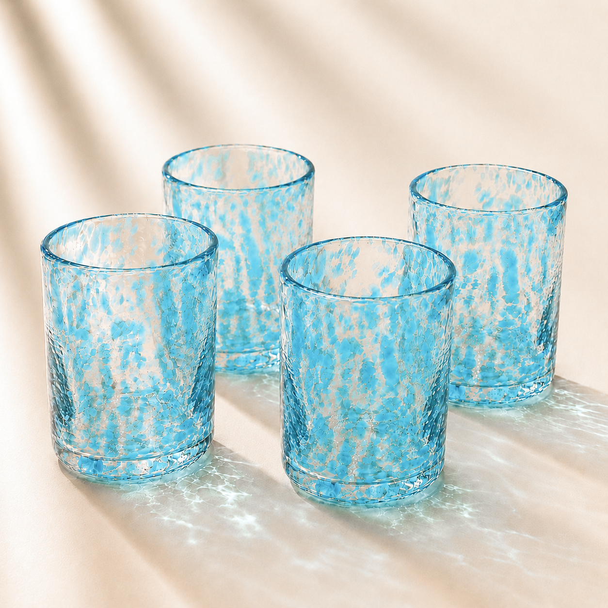 Four spotted glass tumblers with a textured pattern on a beige surface.