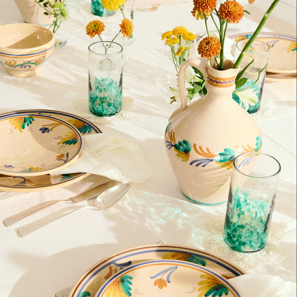 Decorative table setting with floral-patterned plates and vases on a white tablecloth.