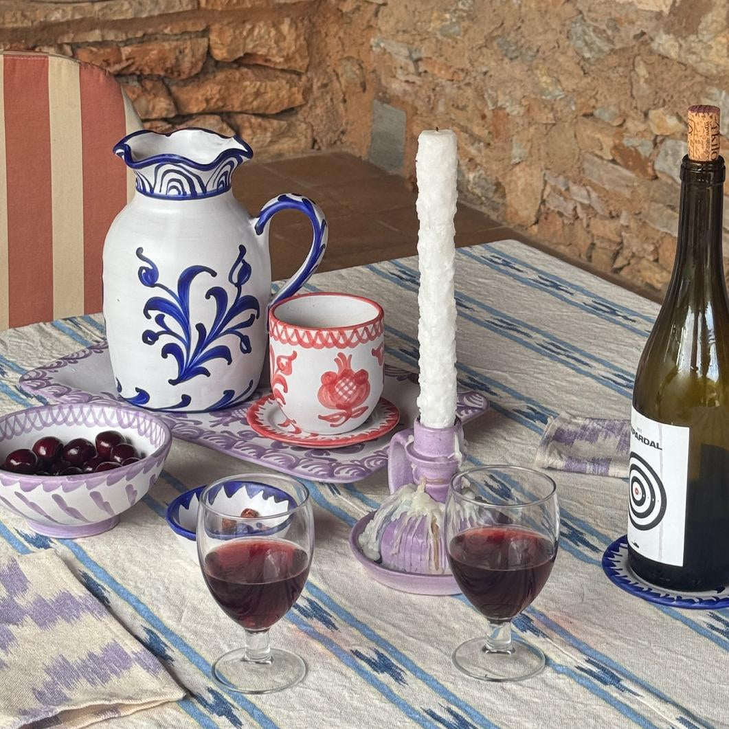 Table setting with wine, glasses, and a bottle in a rustic outdoor setting.