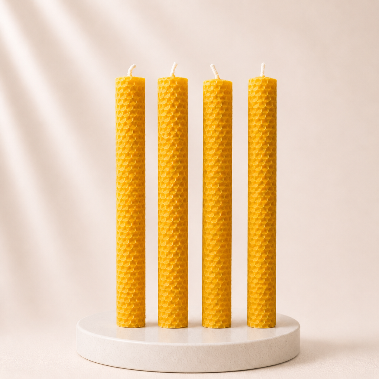 Four yellow textured candles on a white stand against a beige background