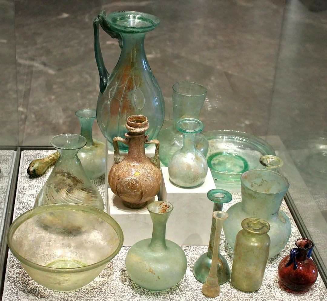 Collection of ancient glass vessels on a reflective surface