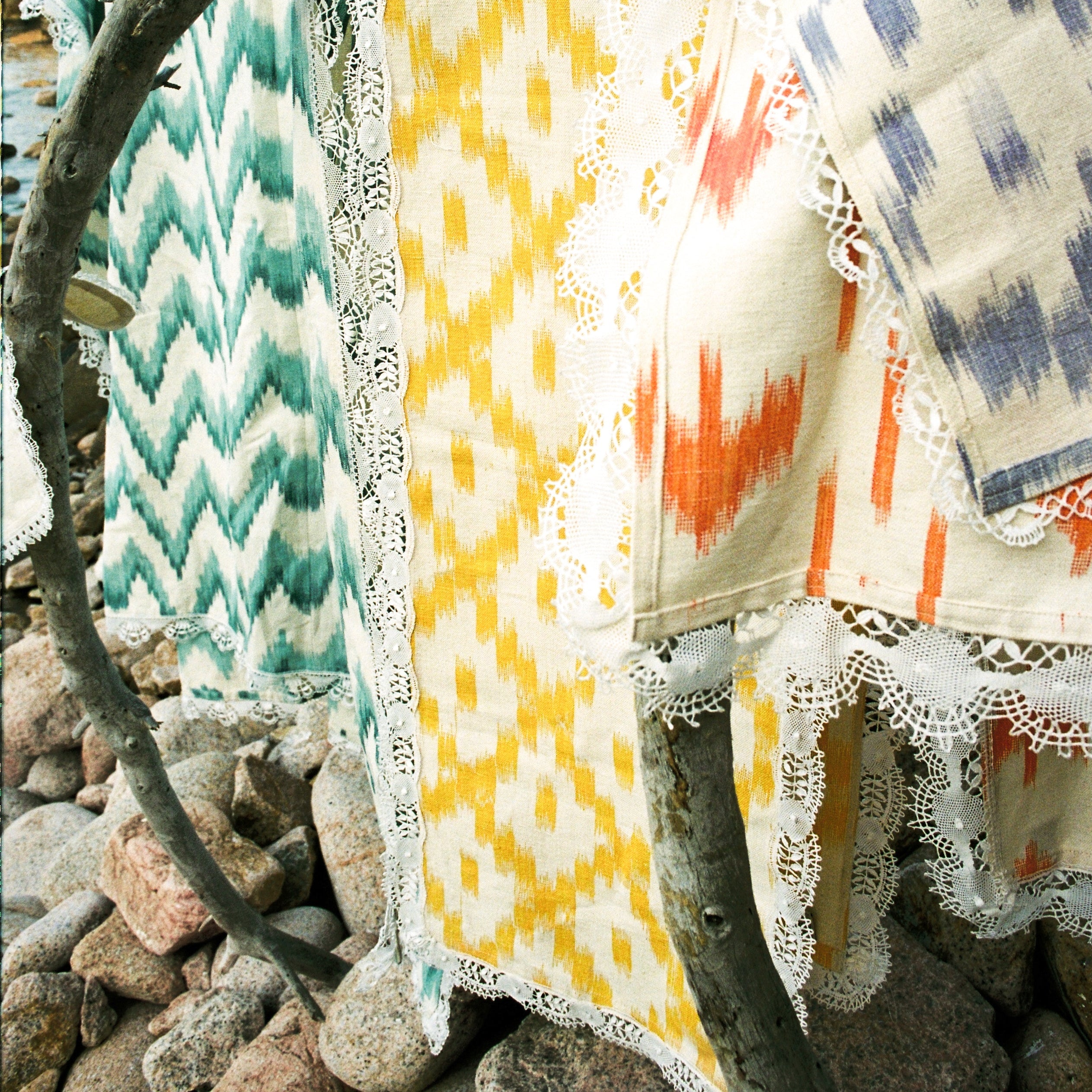 Colorful patterned blankets draped over a branch with a natural background - lifestyle