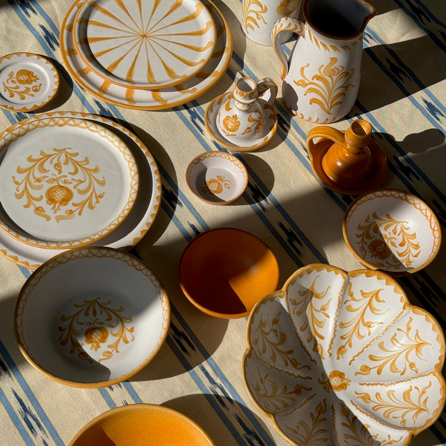 Decorative ceramic tableware with gold patterns on a striped fabric background - lifestyle