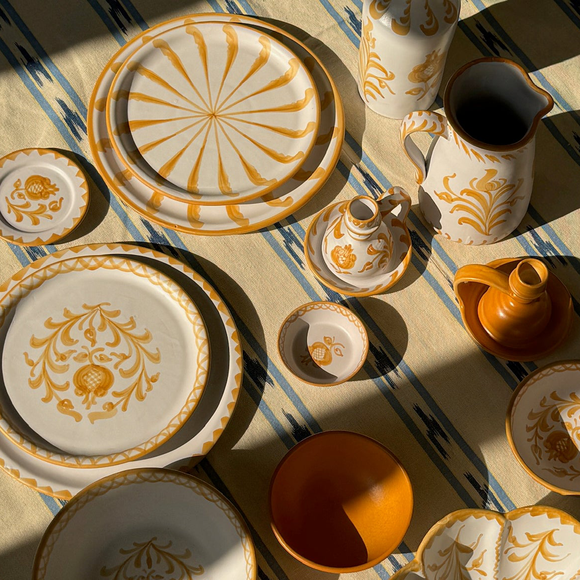 Decorative ceramic tableware with gold patterns on a striped fabric background