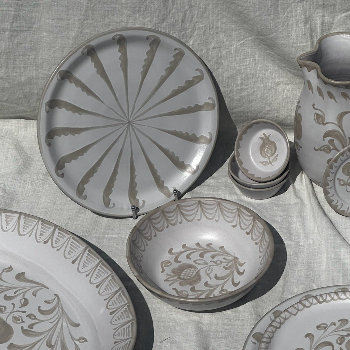 Set of ceramic plates and a pitcher with floral patterns on a textured fabric background