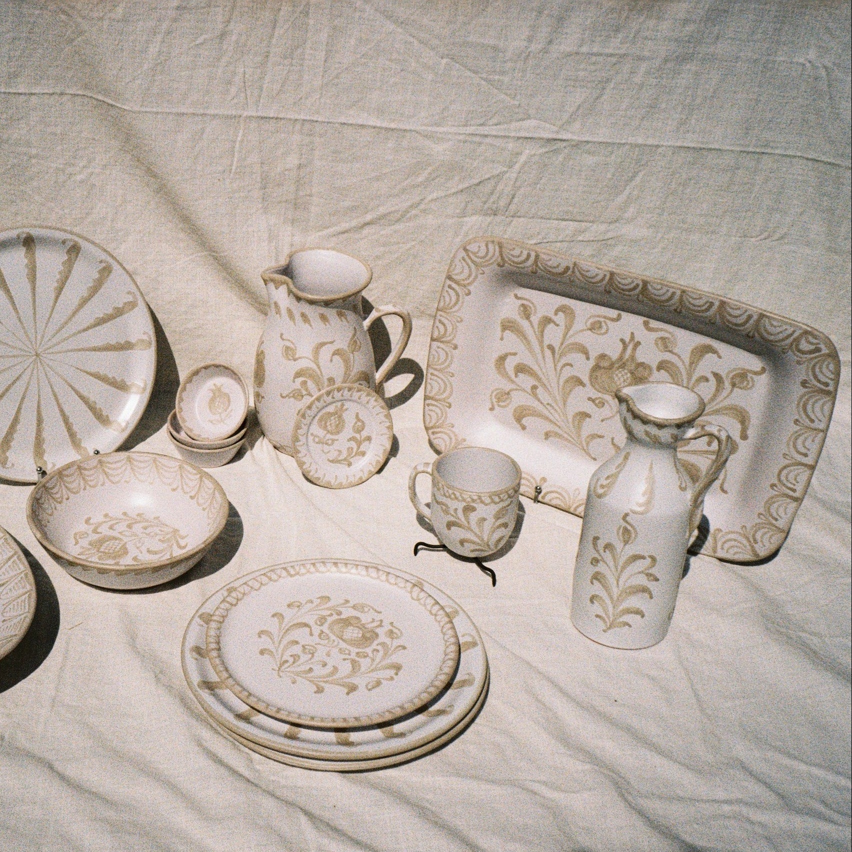 Set of ceramic dishes with floral patterns on a textured fabric background
