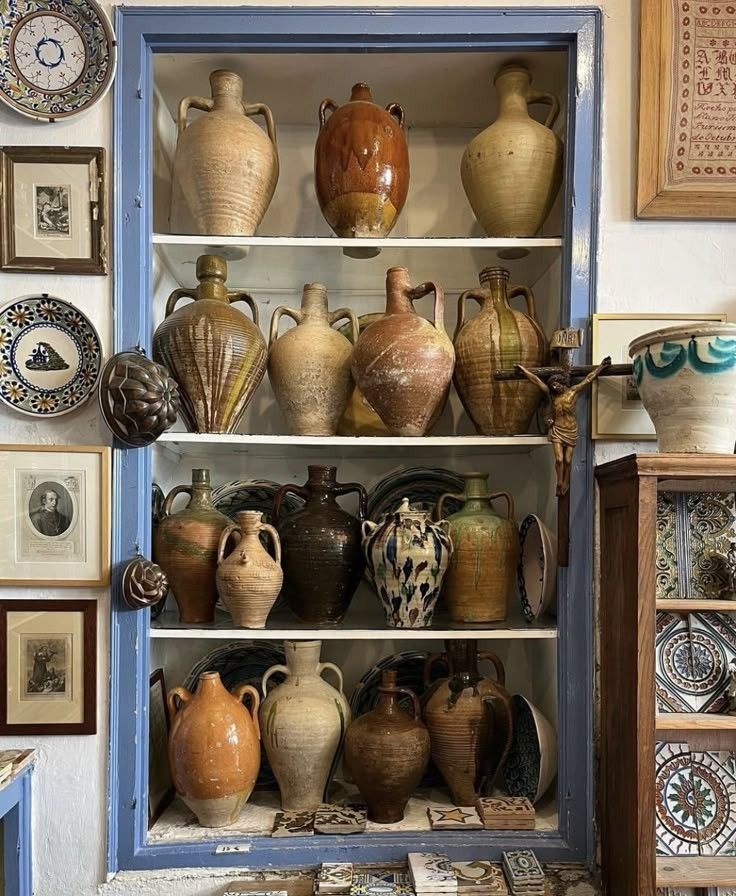 Shelving unit with various ceramic jars and decorative plates on a wall.