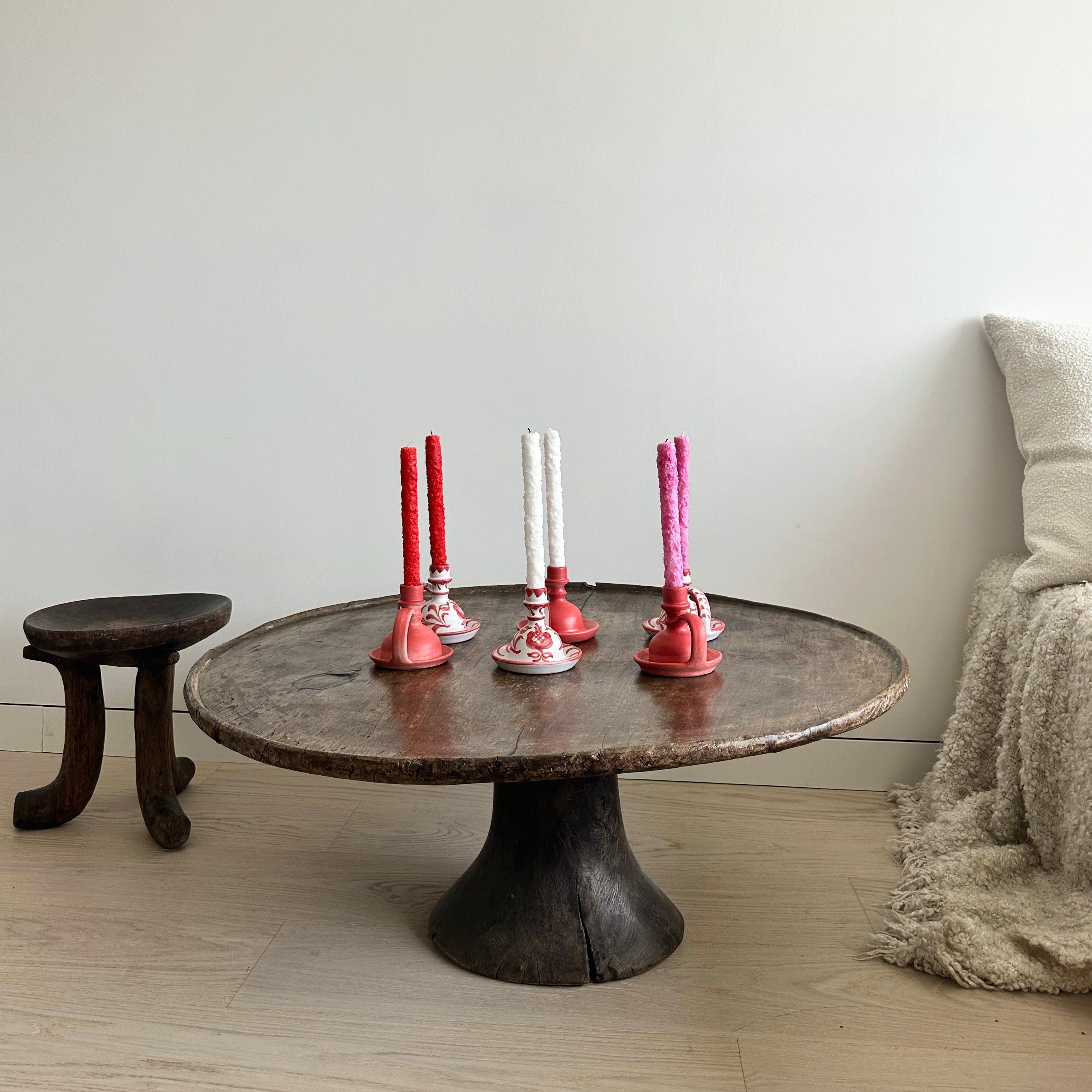 Round wooden table with decorative candle holders in a room setting.