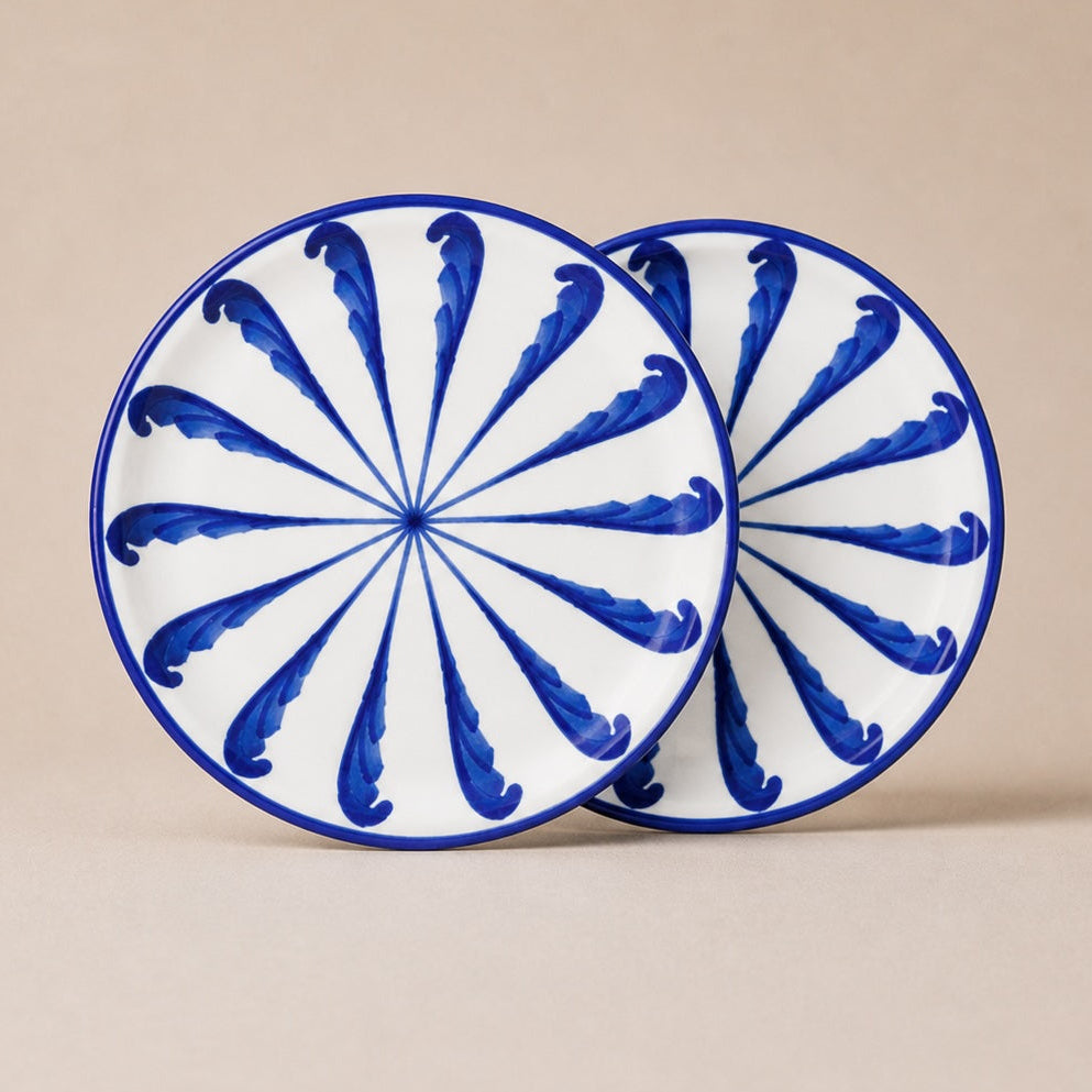 Two ceramic plates with blue and white spiral design on a beige background