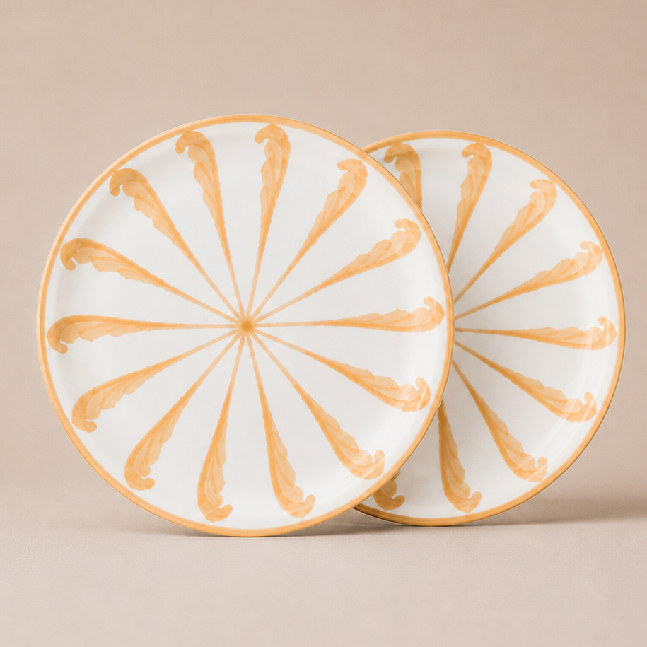 Two ceramic plates with gold decorative patterns on a beige background