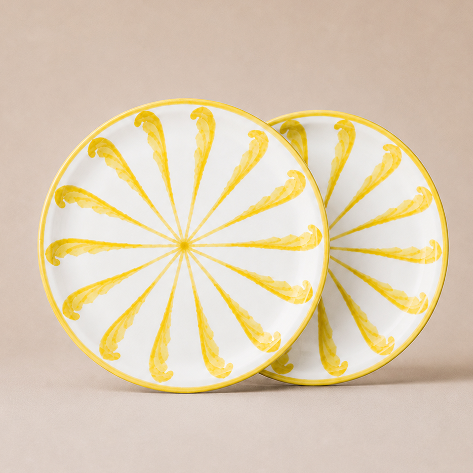 Two ceramic plates with yellow sunburst design on a beige background