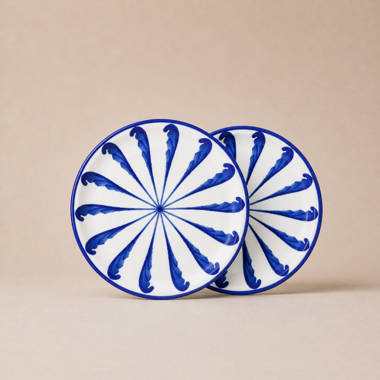 Two ceramic plates with blue and white spiral design on a beige background