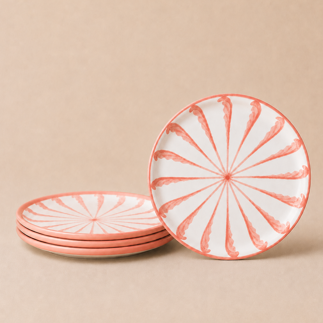 Set of four pink and white patterned plates on a beige background
