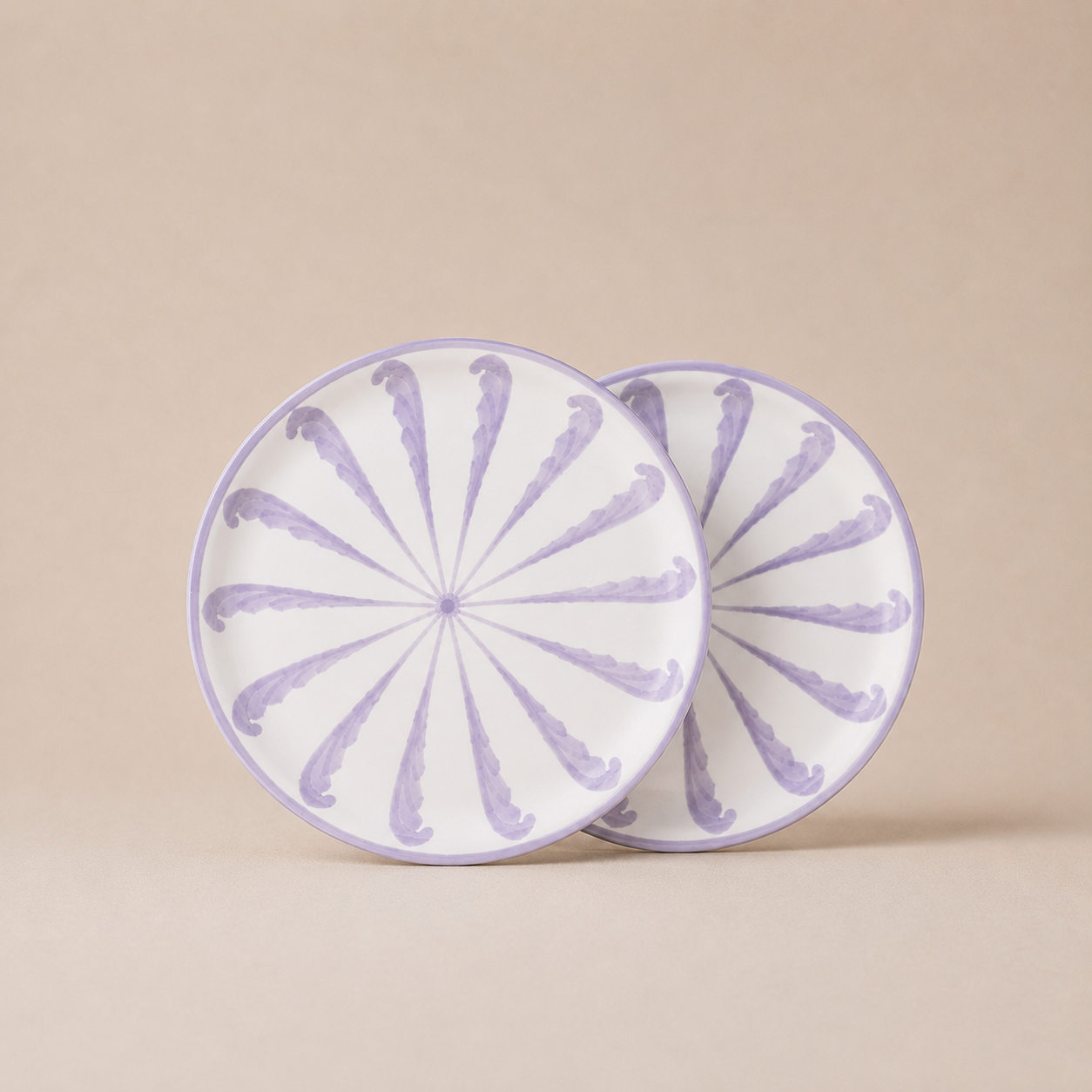 Two round ceramic plates with purple floral patterns on a beige background