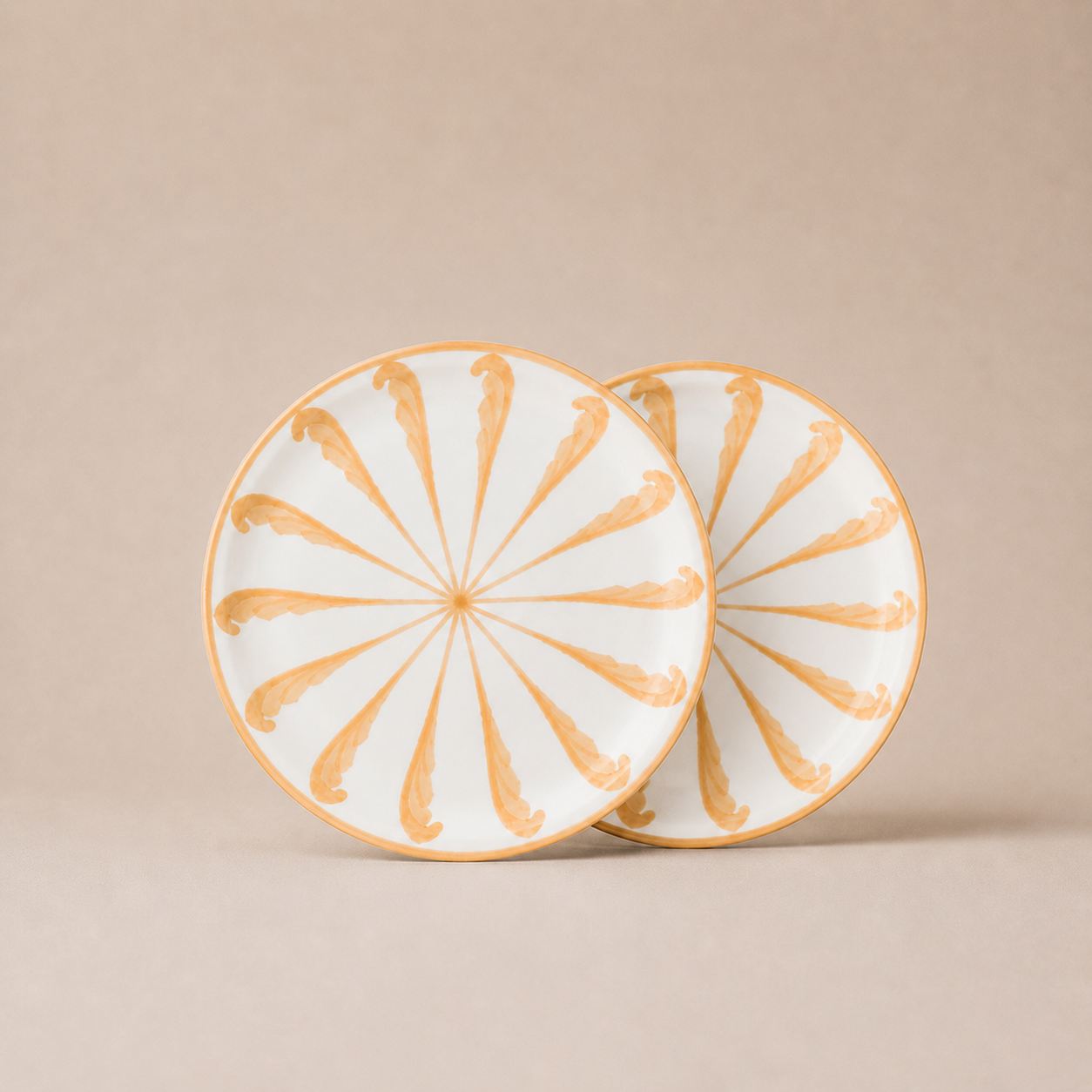 Two ceramic plates with gold decorative patterns on a beige background
