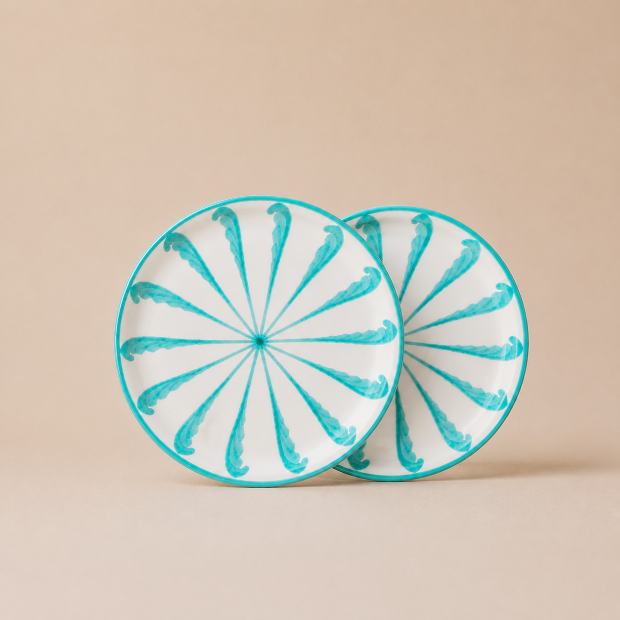 Two round ceramic plates with turquoise spiral patterns on a beige background