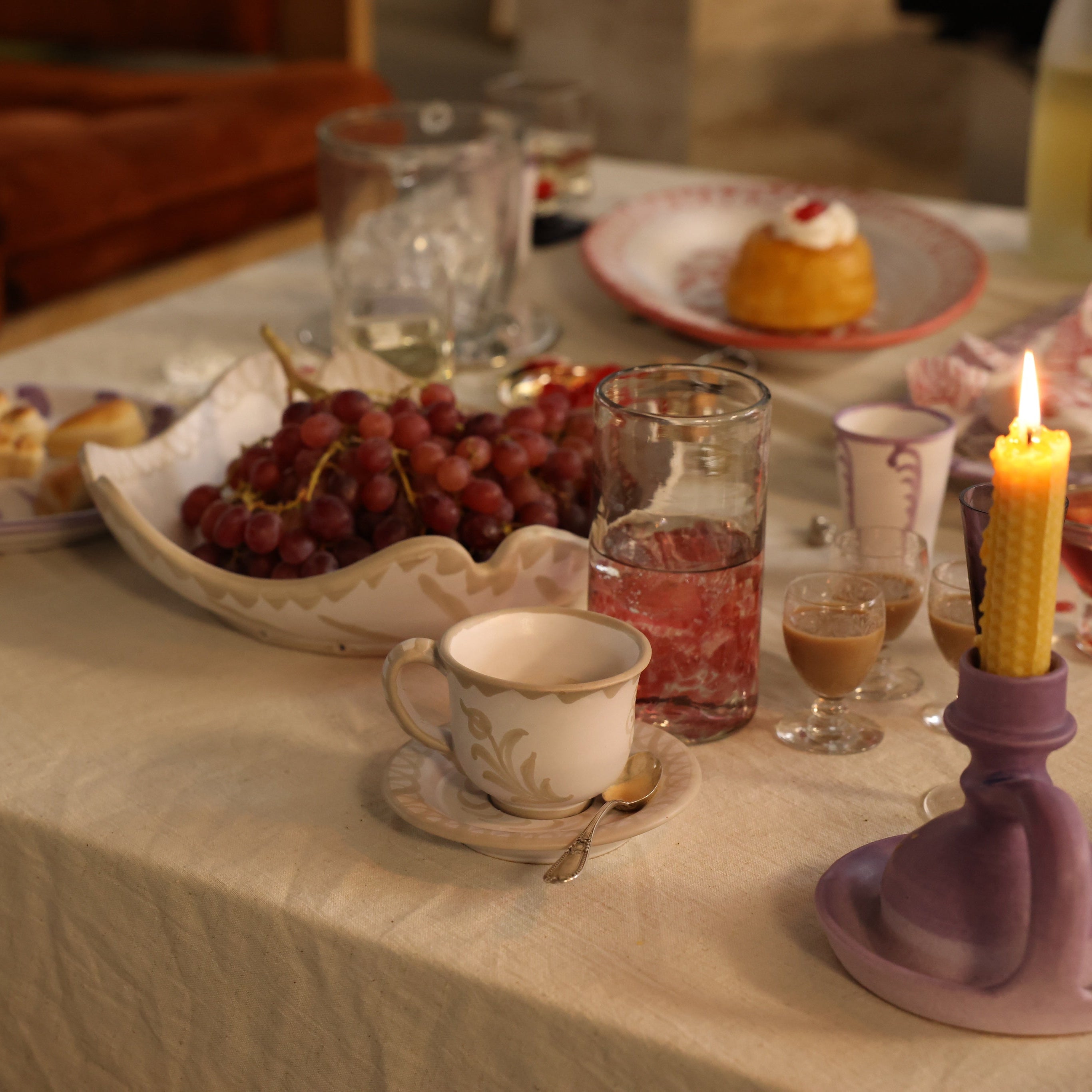 Table setting with tea cup, grapes, and candles in a cozy indoor setting