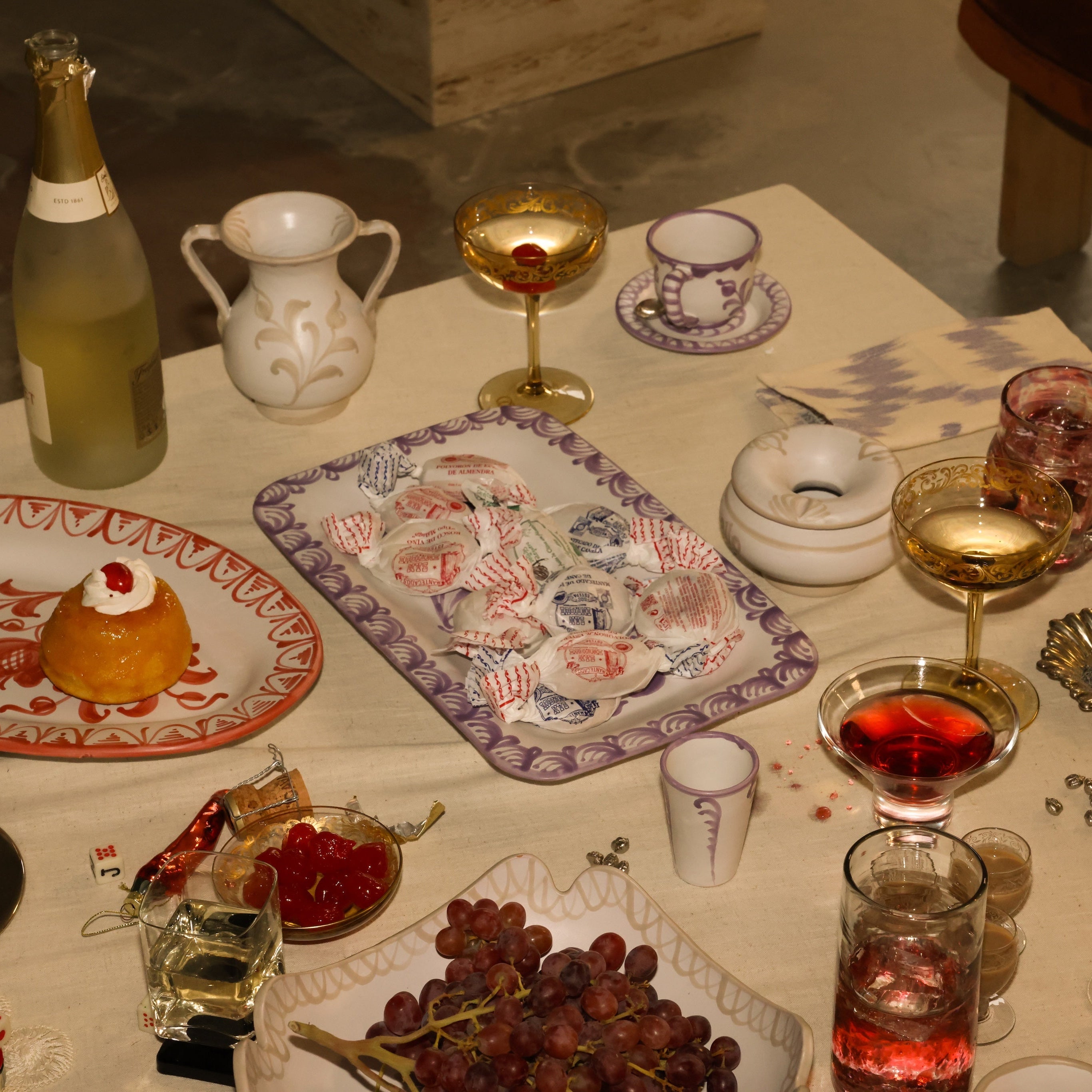 Dessert table with various items including a bottle, glasses, and food.