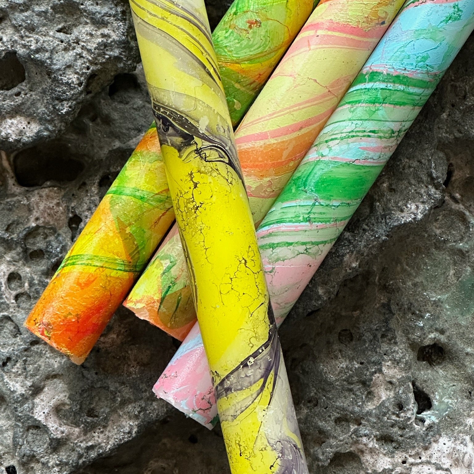 Colorful marbled cylindrical objects on a textured stone surface - lifestyle