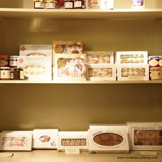 Estanterías con diversos productos alimentarios, entre ellos tarros y cajas, sobre un fondo neutro.