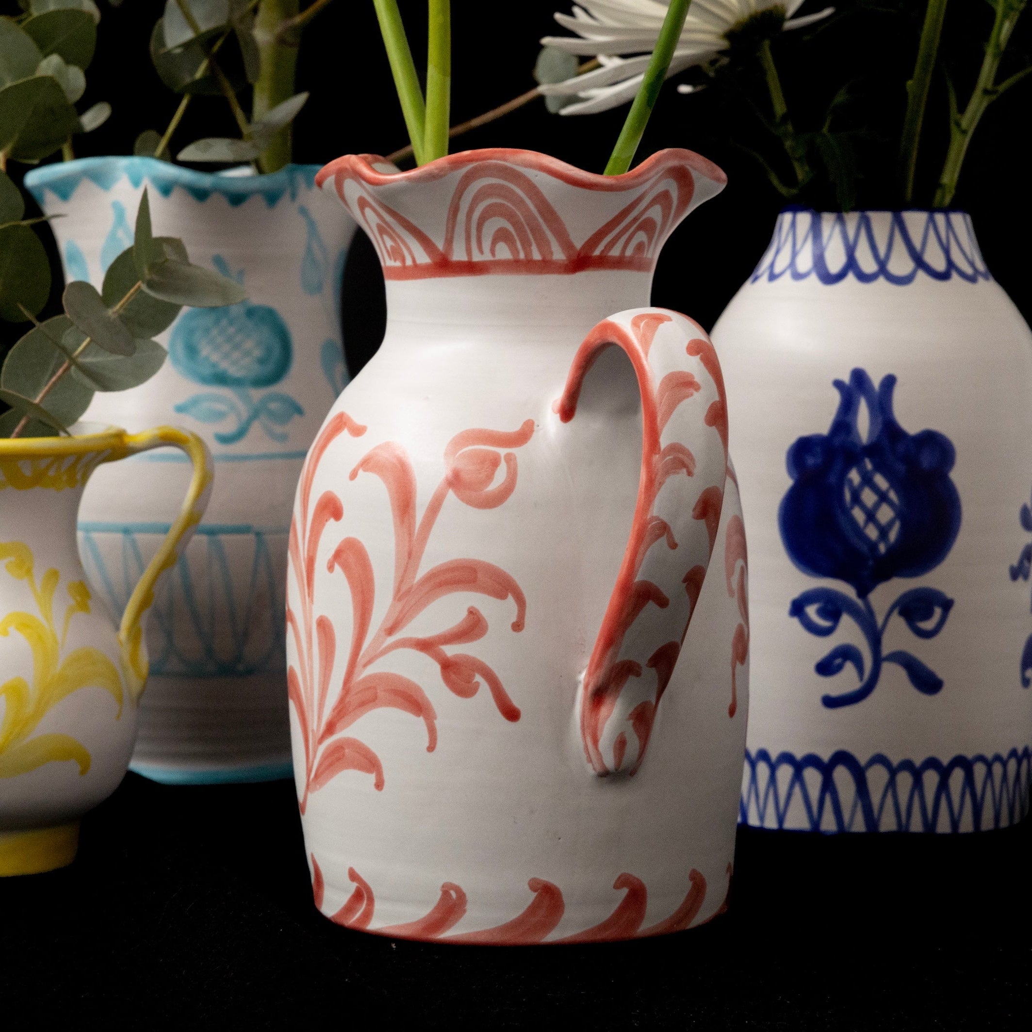 Four decorative vases with floral patterns on a black background