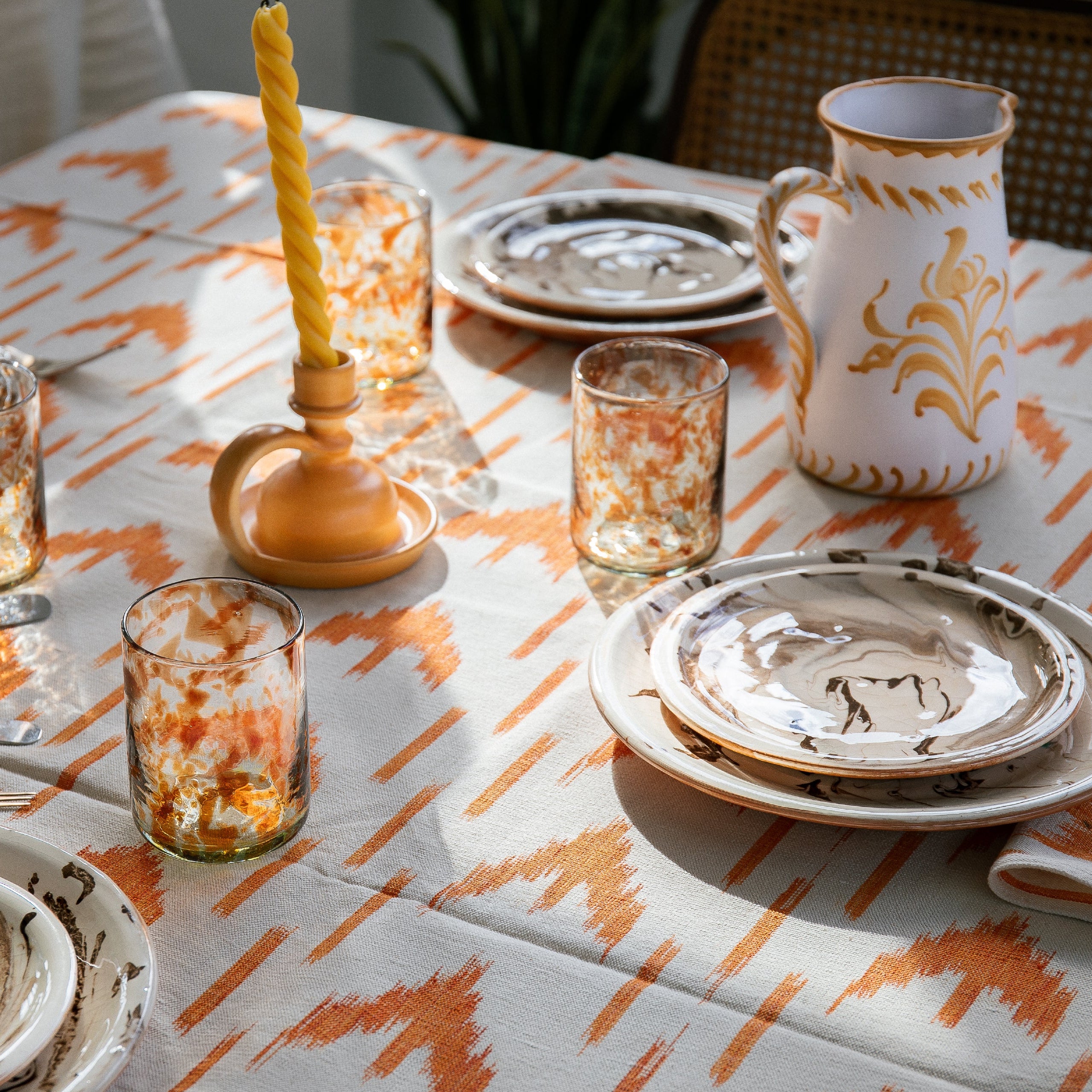Dining table set with plates, glasses, and cutlery on a patterned tablecloth. - lifestyle