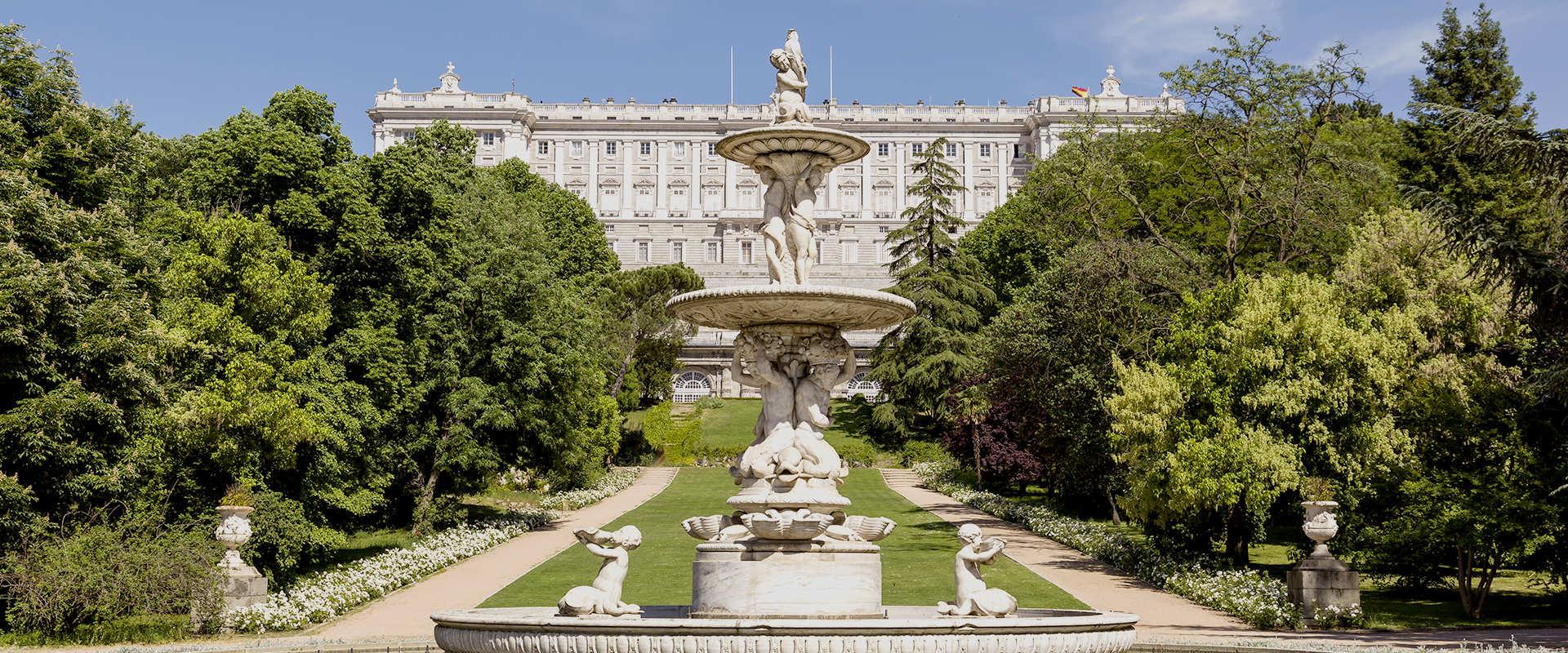 Fuente en un parque con un gran edificio al fondo.